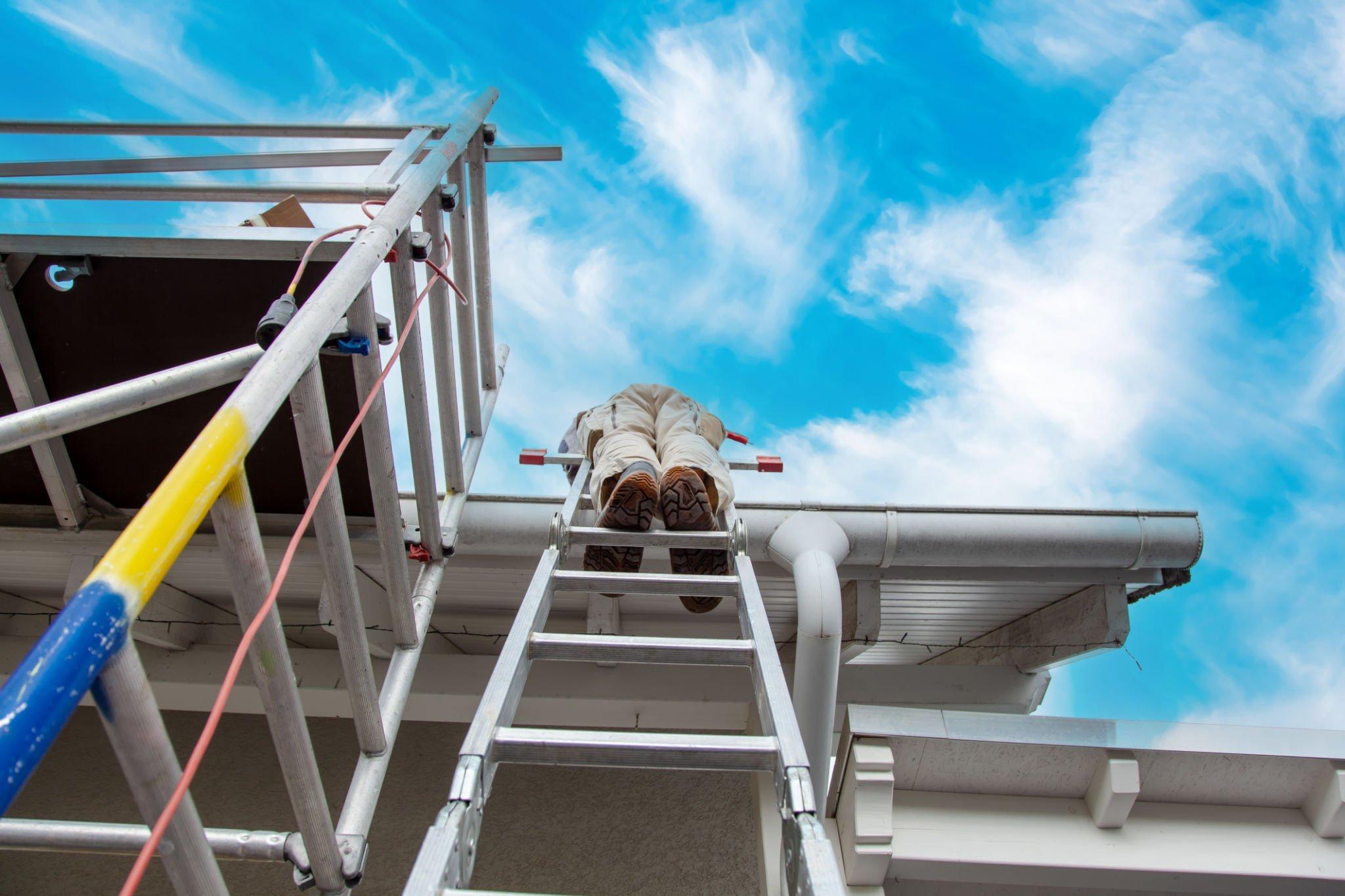 Roofer, worker on the rooftop, standing on a ladder